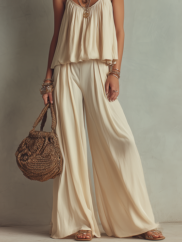 An Off White Flowing Top Paired With Thin Straps And Wide Leg Pants